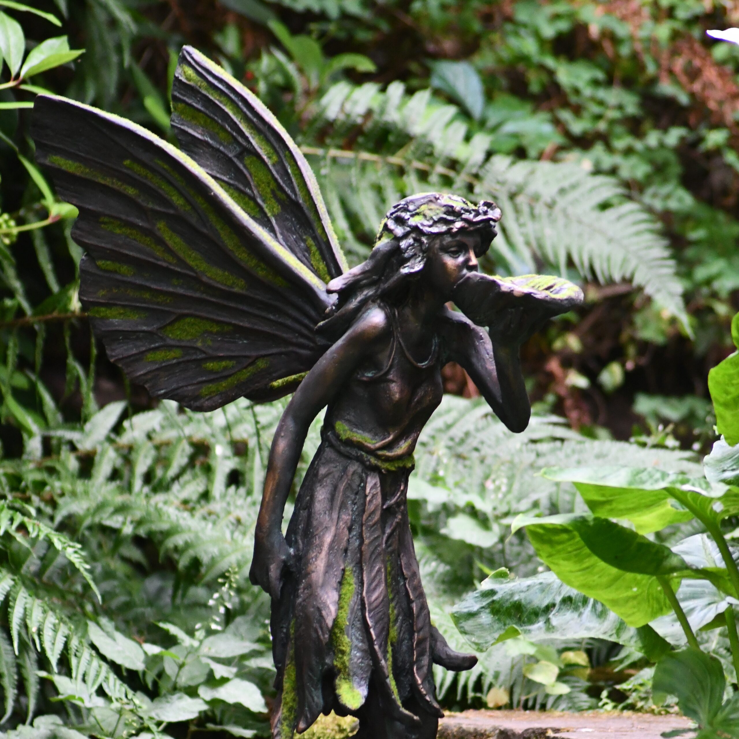 standing moss covered fairy garden ormanent holding a shell